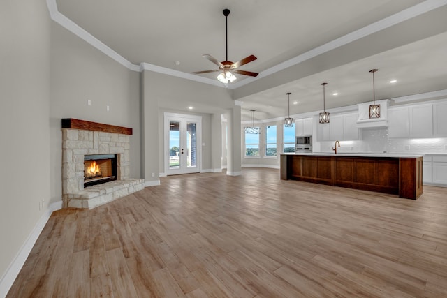 unfurnished living room featuring a fireplace, light hardwood / wood-style floors, ceiling fan, and crown molding