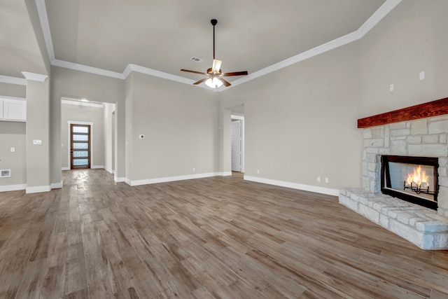 unfurnished living room featuring ornamental molding, hardwood / wood-style floors, a fireplace, and ceiling fan