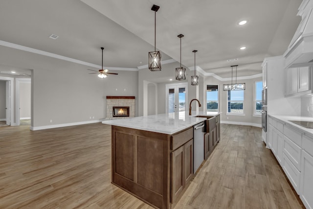 4201 Old Springtown Rd, Weatherford, TX 76085 - kitchen featuring stainless steel appliances, a sink, a stone fireplace, light wood-style flooring, and baseboards
