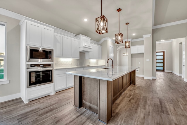 kitchen with plenty of natural light, appliances with stainless steel finishes, an island with sink, and white cabinets