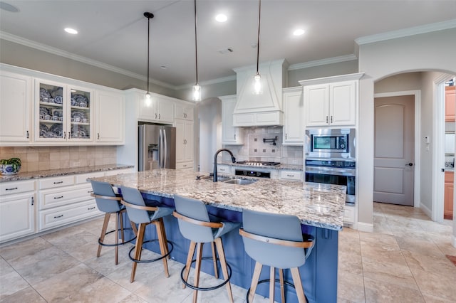 kitchen featuring arched walkways, white cabinets, appliances with stainless steel finishes, crown molding, and a sink