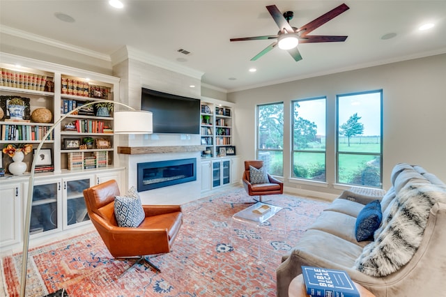 living room with a large fireplace, visible vents, crown molding, and recessed lighting