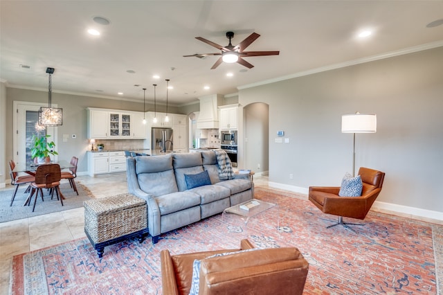 living area with baseboards, arched walkways, a ceiling fan, ornamental molding, and recessed lighting