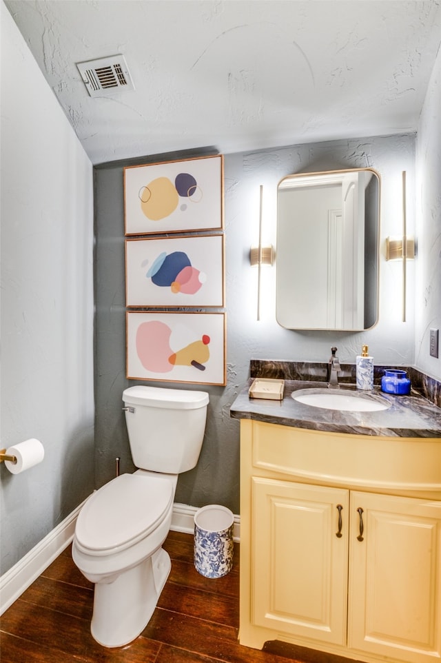 bathroom with toilet, hardwood / wood-style flooring, visible vents, and vanity