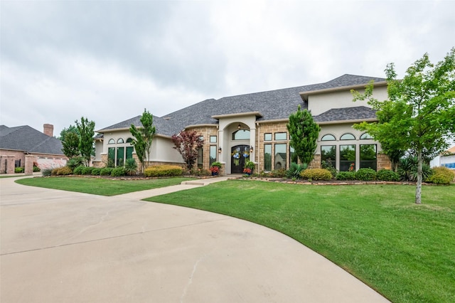 view of front of property with a shingled roof, driveway, a front lawn, and stucco siding