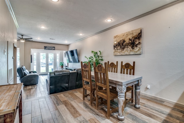 dining area featuring french doors, ornamental molding, light wood-type flooring, and ceiling fan