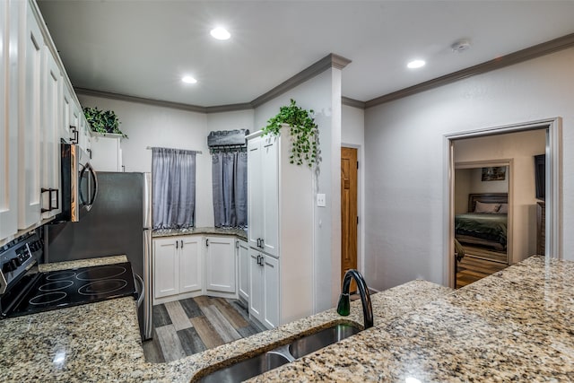 kitchen with white cabinets, range with electric stovetop, light stone countertops, wood-type flooring, and ornamental molding