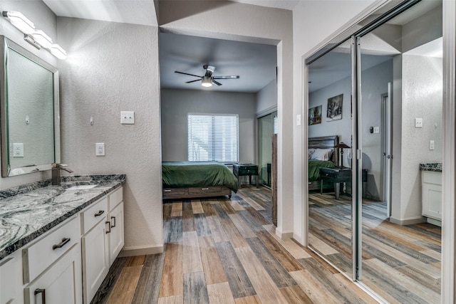 bathroom with ceiling fan, vanity, and wood-type flooring