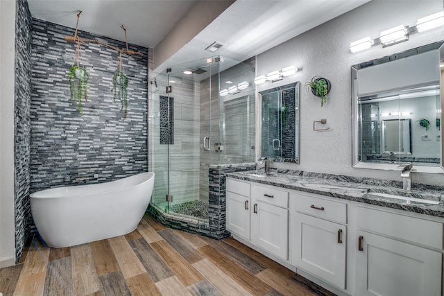 bathroom featuring plus walk in shower, double sink vanity, and tile walls