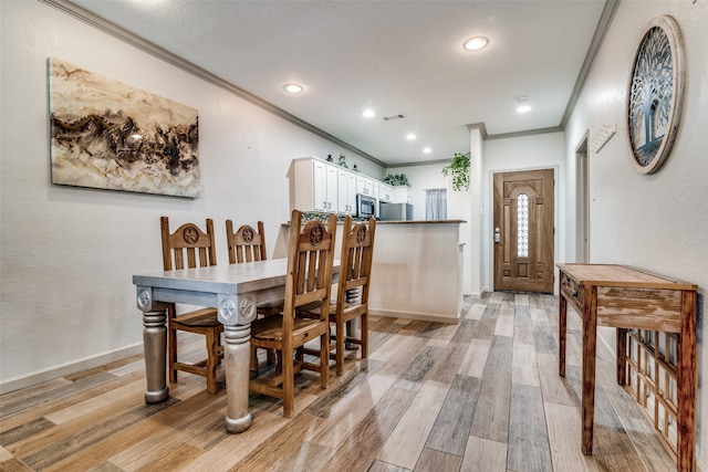 dining space with ornamental molding and light wood-type flooring