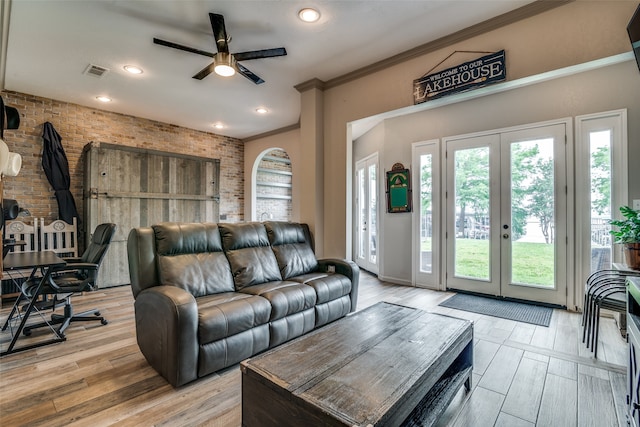 living room with brick wall, plenty of natural light, french doors, and light wood-type flooring