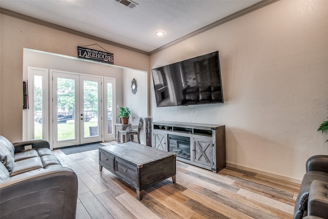 living room featuring light hardwood / wood-style flooring, ornamental molding, and french doors