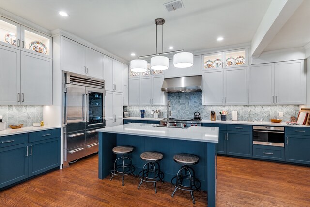 kitchen featuring tasteful backsplash, wall chimney range hood, blue cabinets, and hardwood / wood-style floors