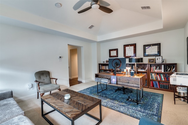 office area with ceiling fan, carpet floors, and a tray ceiling