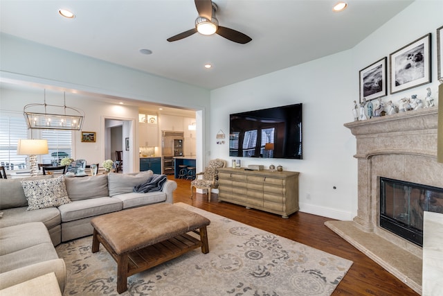 living room featuring a premium fireplace, dark hardwood / wood-style flooring, and ceiling fan