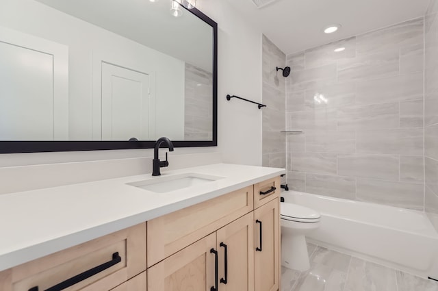 full bathroom featuring tiled shower / bath, vanity, and toilet