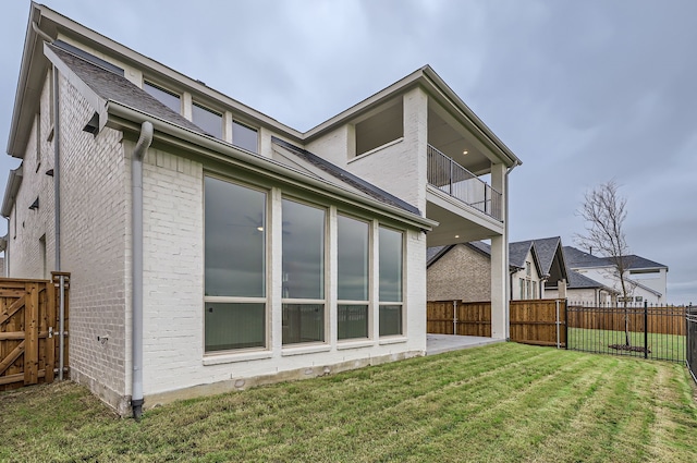 back of property with a balcony and a yard