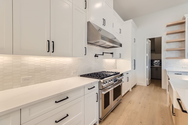 kitchen with range with two ovens, white cabinetry, light hardwood / wood-style floors, and tasteful backsplash