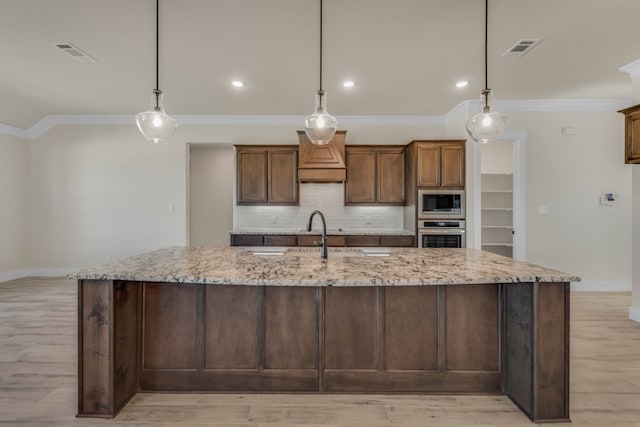 kitchen with stainless steel appliances, light stone counters, and hanging light fixtures