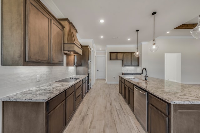 kitchen with pendant lighting, light wood-type flooring, light stone counters, sink, and backsplash