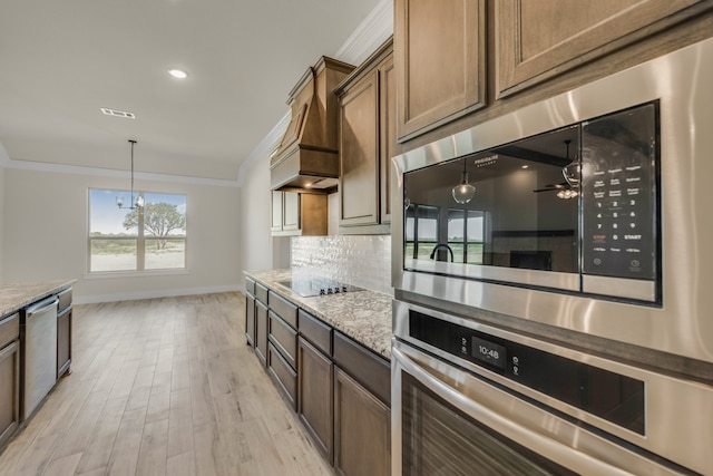 kitchen featuring ceiling fan, appliances with stainless steel finishes, light stone countertops, crown molding, and light hardwood / wood-style floors