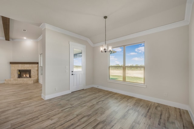 unfurnished dining area featuring ornamental molding, light hardwood / wood-style floors, a fireplace, and a notable chandelier