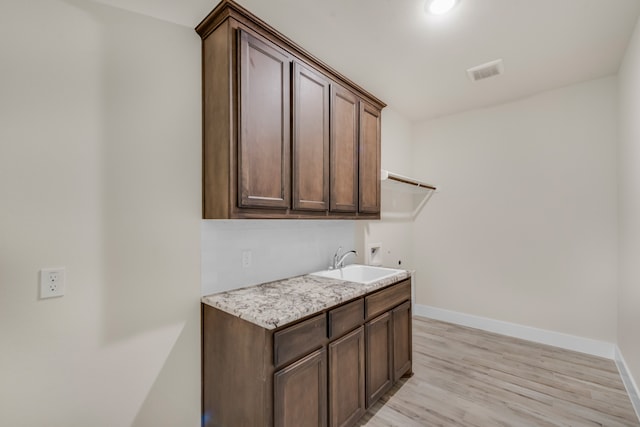 interior space featuring hookup for a washing machine, light wood-type flooring, sink, and cabinets