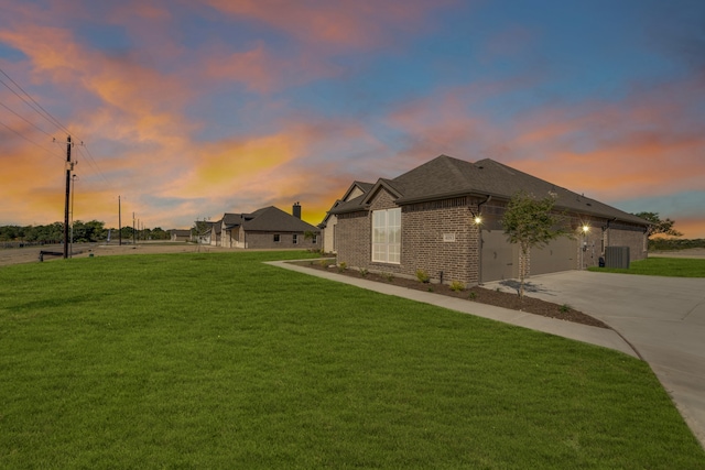 view of front of property with a garage, central air condition unit, and a yard