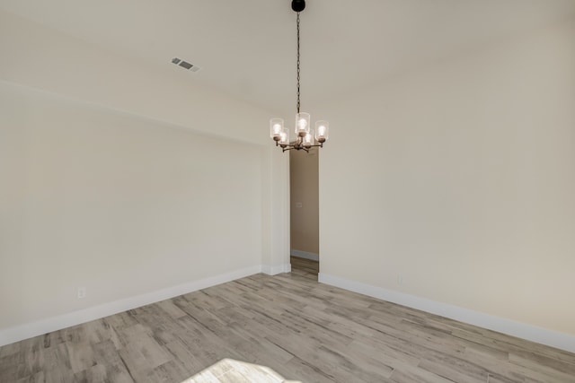 unfurnished room with an inviting chandelier and light hardwood / wood-style floors