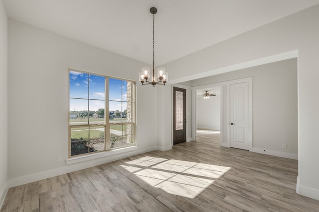 unfurnished dining area featuring ceiling fan with notable chandelier and light hardwood / wood-style floors