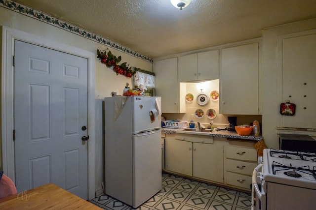 kitchen with sink, a textured ceiling, and white appliances