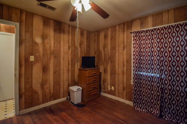 unfurnished bedroom featuring ceiling fan, wooden walls, and dark hardwood / wood-style flooring