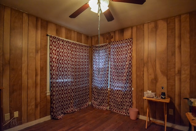 empty room featuring hardwood / wood-style flooring, wooden walls, and ceiling fan