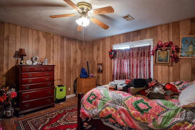 bedroom with ceiling fan and wood walls