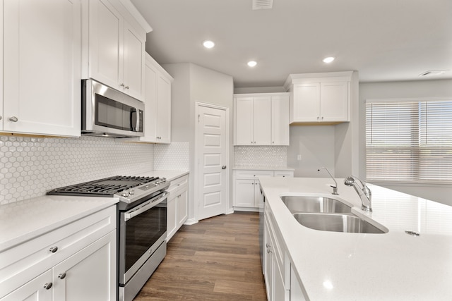 kitchen with appliances with stainless steel finishes, white cabinetry, a sink, and dark wood-type flooring