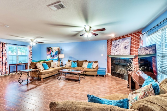 living room featuring a healthy amount of sunlight, hardwood / wood-style floors, a tile fireplace, and ceiling fan