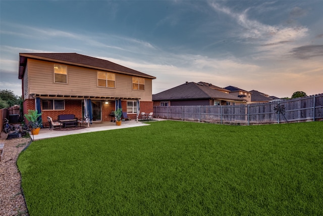 back house at dusk with a yard and a patio