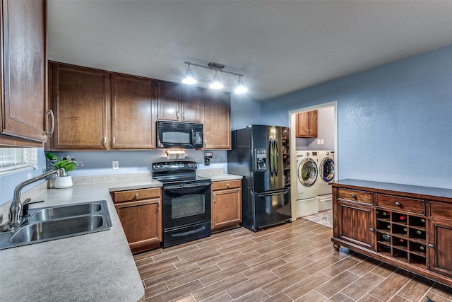 kitchen featuring track lighting, separate washer and dryer, light wood-type flooring, black appliances, and sink