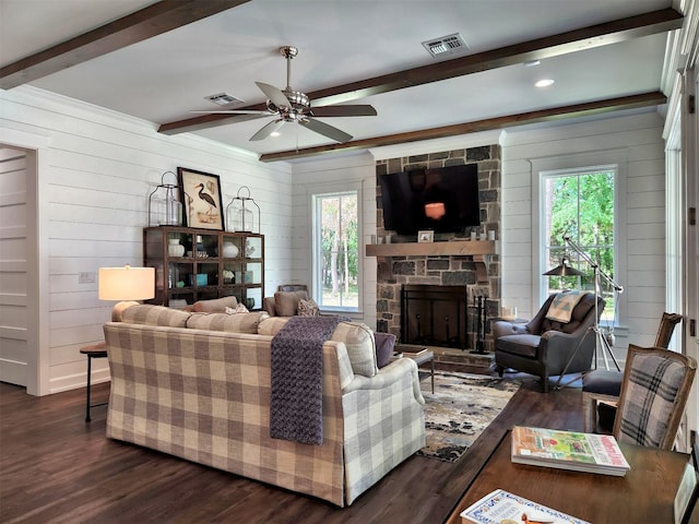 living room with a wealth of natural light, a stone fireplace, and dark hardwood / wood-style floors