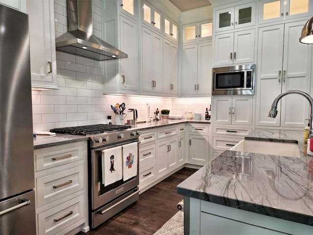 kitchen featuring appliances with stainless steel finishes, tasteful backsplash, dark wood-type flooring, wall chimney exhaust hood, and white cabinetry