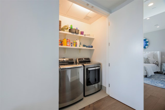 clothes washing area with light wood-type flooring and washing machine and clothes dryer