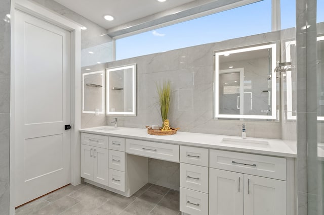 bathroom featuring tile floors, dual vanity, backsplash, and tile walls