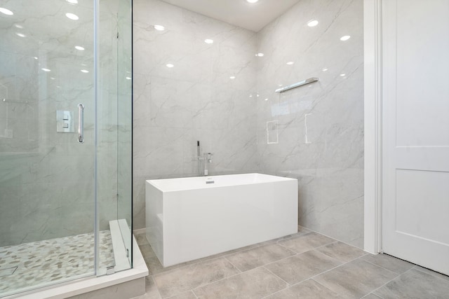 bathroom with tile walls, tile flooring, and separate shower and tub