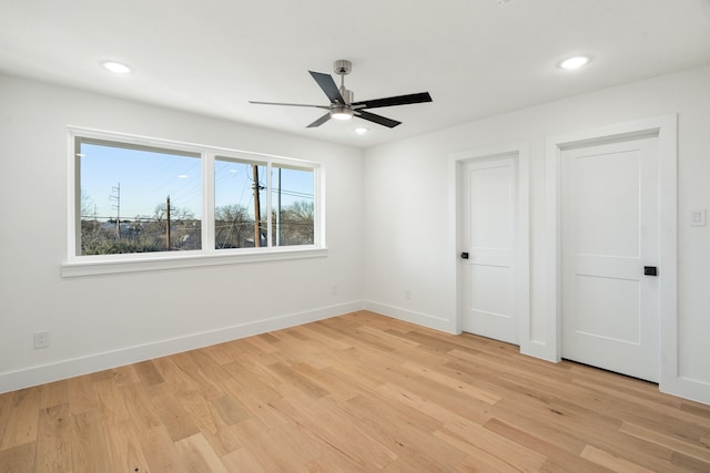 spare room with a healthy amount of sunlight, ceiling fan, and light hardwood / wood-style flooring