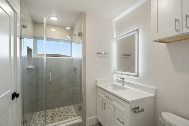 bathroom featuring a shower with door, oversized vanity, and toilet