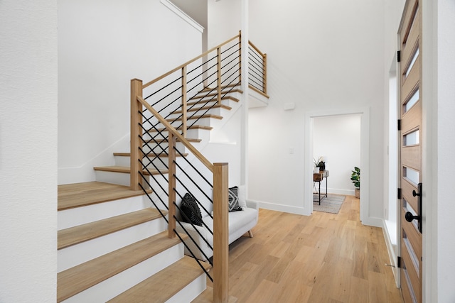 stairway with a towering ceiling and light hardwood / wood-style flooring