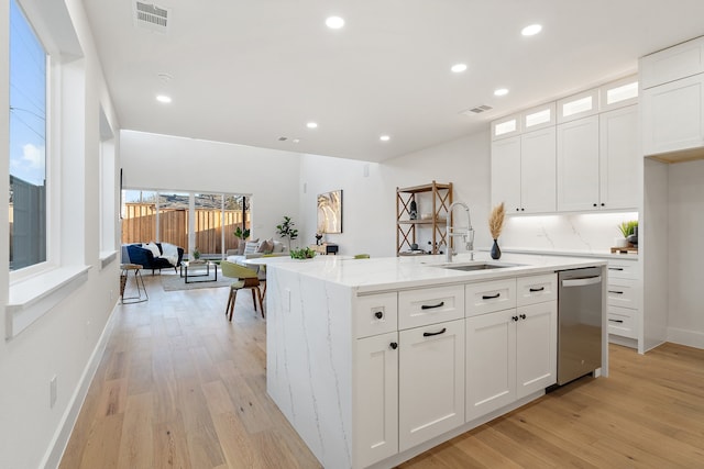 kitchen featuring white cabinetry, light hardwood / wood-style floors, a kitchen island with sink, sink, and dishwasher