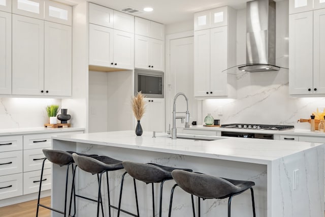 kitchen featuring white cabinetry, wall chimney exhaust hood, and light hardwood / wood-style flooring