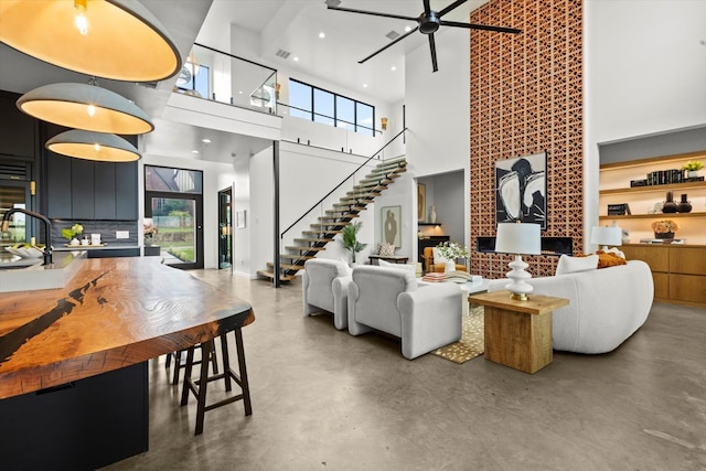 living room with a high ceiling, ceiling fan, concrete flooring, and sink