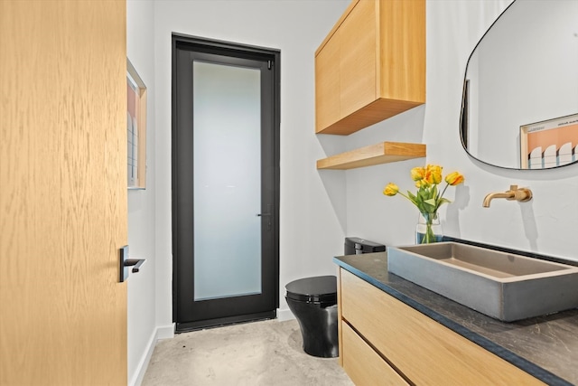 bathroom with concrete floors, oversized vanity, and toilet